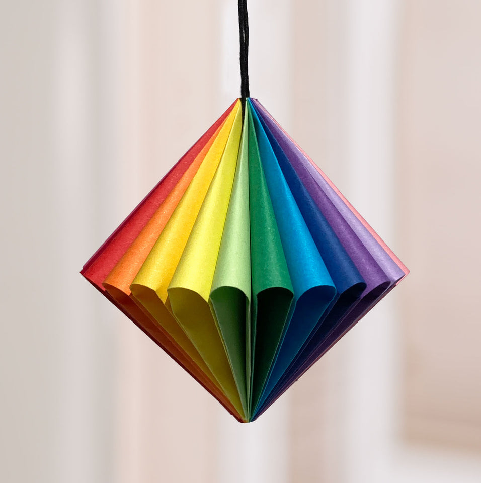 13 colors of origami paper created this 3 inch X 3 inch pendant. 26 folded curves hold the ornament's shape. No glue is used. Just 13 pieces of paper, two staples and a string. 